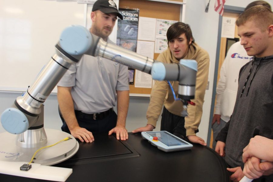 Evan Niemeyer (center) and Caleb Parker (right) observe a robotic arm displayed by Flexline at the career fair.