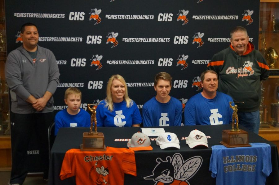 Jarrett+James%2C+flanked+by+his+family+and+coaches%2C+signs+a+letter+of+intent+to+play+golf+at+Illinois+College.