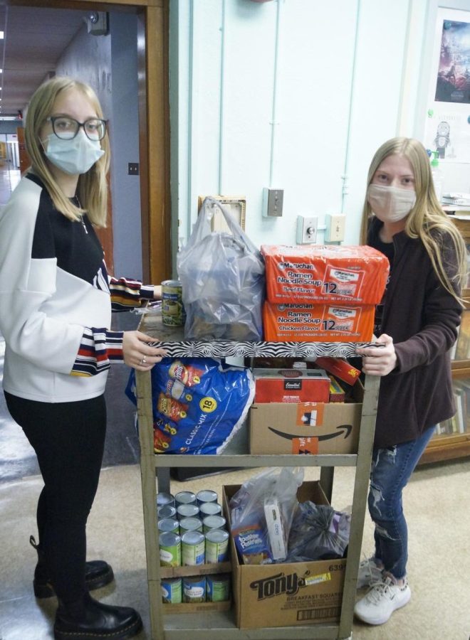 Abby Bollmann and Megan Miller of the National Honor Society display the 101 items collected from the first period Rhetoric & Composition class.