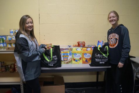 Mrs. Kern and Hanna Colvis prepare food bags for the Just for Jackets program.