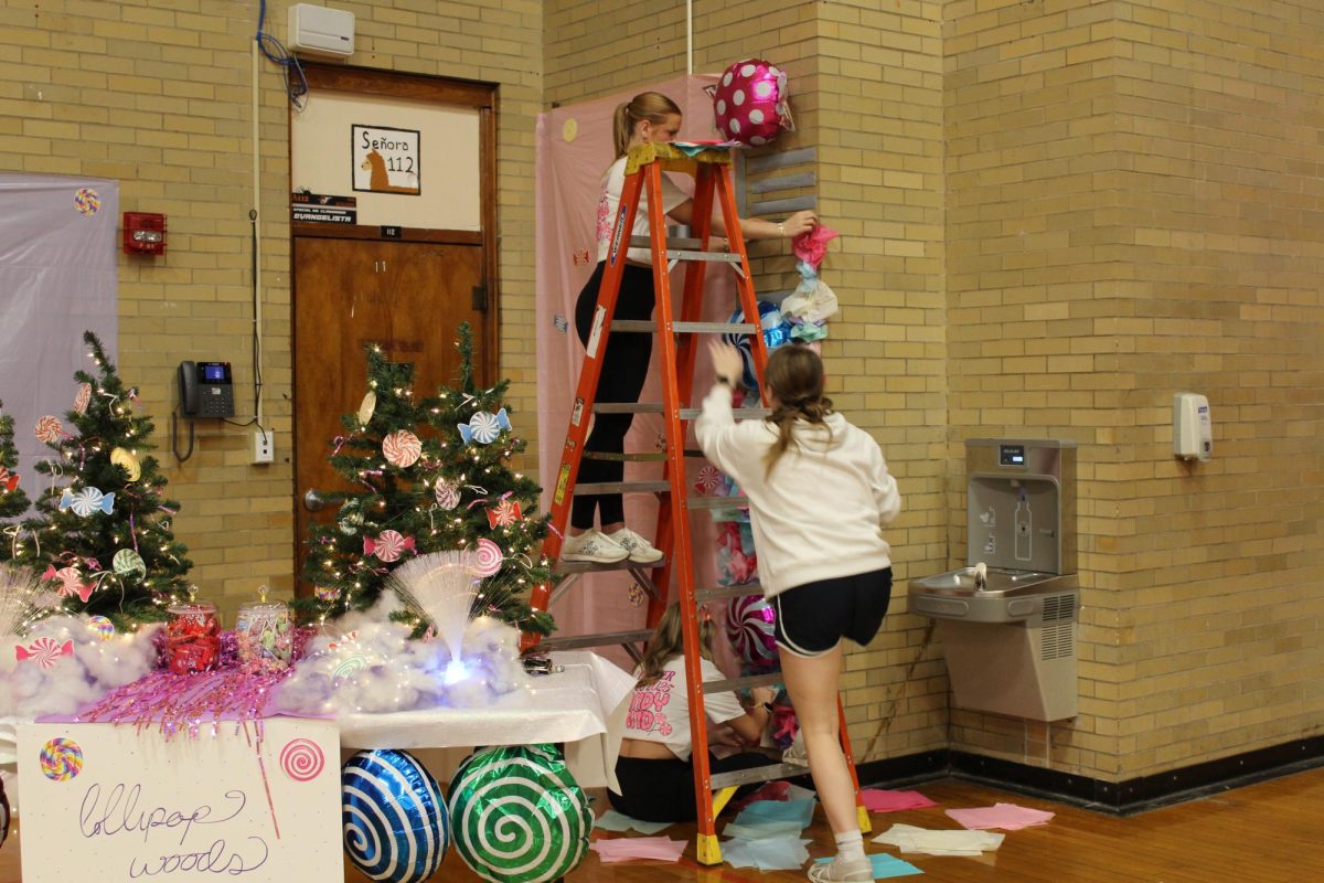 Maggie Caby, Jessica Stumpe, and Callie Davis putting up candy wall